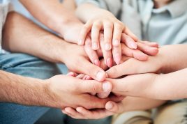 Close-up of several hands placed on top of one another in stack. All family members showing their support to each other. Concept of togetherness, unity, teamwork, family, solidarity, mutual support.
